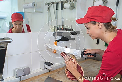 Female butcher slicing meat Stock Photo