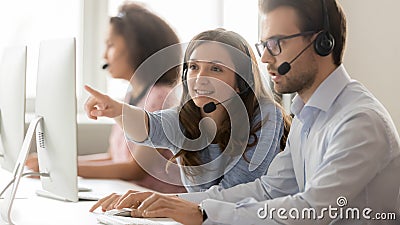 Female call center agent helping male colleague pointing at computer Stock Photo