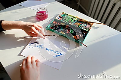 Female calligrapher creates inscription for sale, using brushes Stock Photo