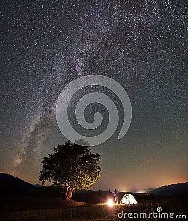 Woman resting at night camping in mountains under starry sky Stock Photo