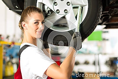 Female car mechanic working on jacked auto Stock Photo