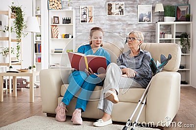 Female care giver reading a story from a book to a senior woman Stock Photo