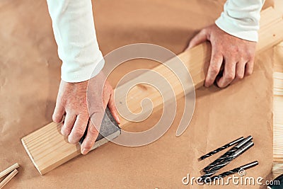 Female carpenter manually sanding wooden plank Stock Photo