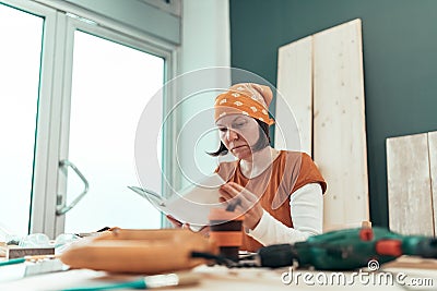 Female carpenter reading DIY project instruction manual Stock Photo