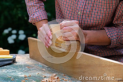 Female carpenter working with old wooden jointer plane. Wood shaving tool, woodwork, DIY concept Stock Photo
