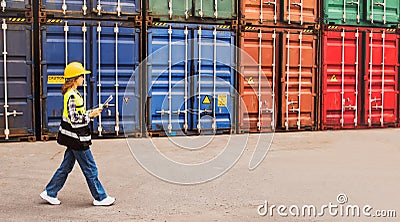 female caucasianl engineering worker wearing safety helmet holding clipboard walking checking cargo container. Stock Photo