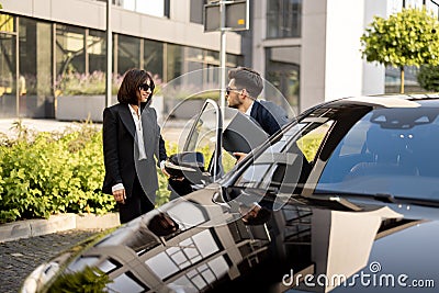 Female chauffeur helps a businessman to get out of the car Stock Photo