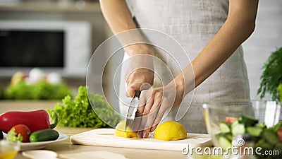 Female chef cutting lemon with sharp knife for lunch preparing, cooking tips Stock Photo