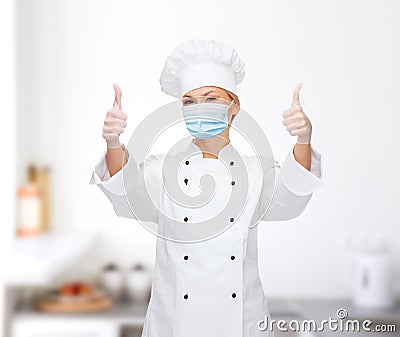 Female chef in face mask showing thumbs up Stock Photo