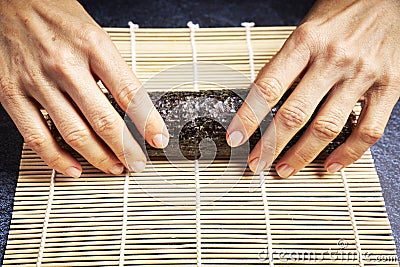 Female chef preparing a roll with rice and nori for a delicious sushi. Asian food concept Stock Photo