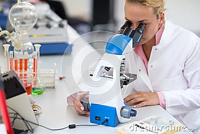 Female chemist exam sample of liquid with microscope Stock Photo