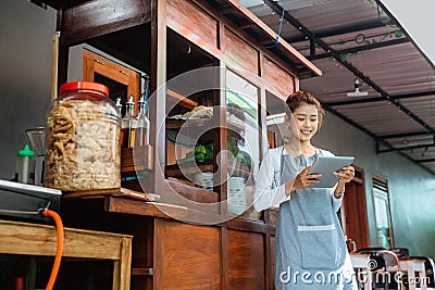 female chicken noodle vendor in apron using a pad Stock Photo