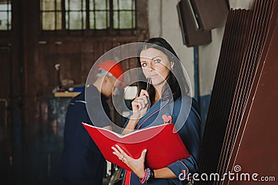 Female chief stands against a worker, during he works at metal c Stock Photo