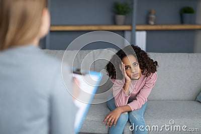 Female child psychologist working with upset black girl, teenager patient talking about her feelings Stock Photo