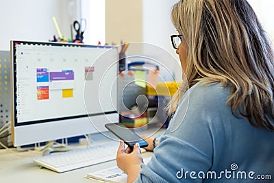 Female child therapist in an office during a phone call, using online calendar to schedule patients appointments. Calendar Planner Stock Photo