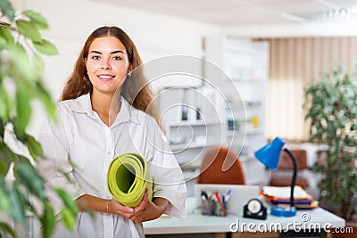 Female clerical worker holding rolled-up mat in hands Stock Photo