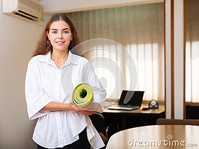 Female clerical worker holding rolled-up mat in hands Stock Photo