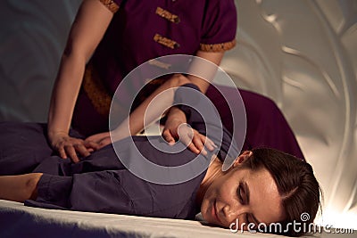 Massage therapist doing diagonal stretch and elongation of patient spine Stock Photo