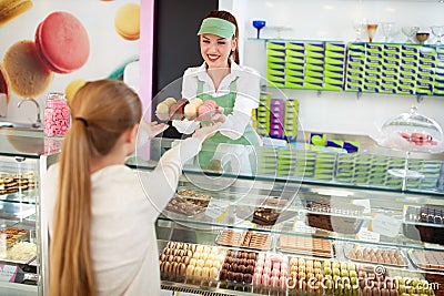 Female confectioner sales delicious macarons to girl Stock Photo