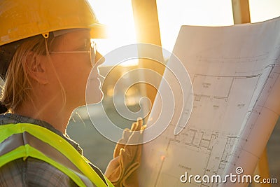 Female Construction Worker with House Plans at Construciton Site Stock Photo