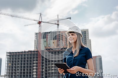 Female construction engineer. Architect with a tablet computer at a construction site. Young Woman looking, building Stock Photo