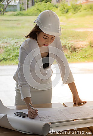 Female construction site engineer/Young engineers are checking the plan. Stock Photo