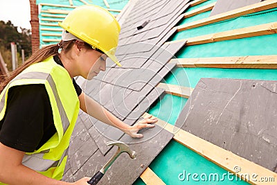 Female Construction Worker On Site Laying Slate Tiles Stock Photo