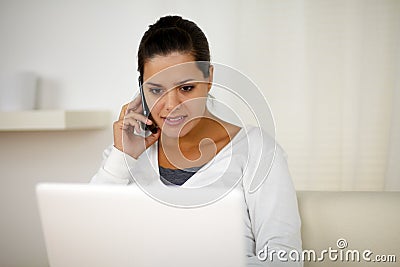 Female conversing on cellphone in front of laptop Stock Photo
