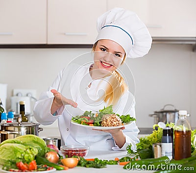 Female cook arranging herbs decoration on plate with salad Stock Photo