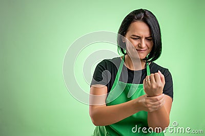Female cook with green apron and black t-shirt has wrist pain Stock Photo