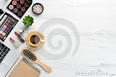 Female cosmetics on white office desk. Laptop, notepad, Lipstick, powder, comb, women`s jewelry. Stock Photo