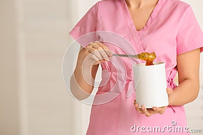 Female cosmetologist holding jar with sugaring paste for depilation in beauty salon Stock Photo