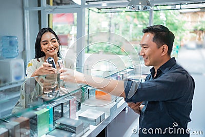 female customer checking the vape mod helped by the male shopkeeper Stock Photo