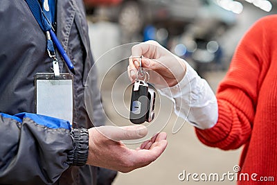 Female customer in garage. Technical repairman take car key at woman. Mechanical repair client car in auto service shop. Stock Photo