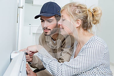 Female customer watching male plumber work Stock Photo