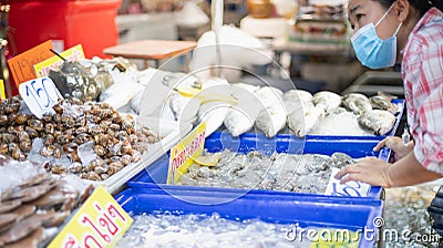 Female customers choosing fresh raw shellfish seafoods from large assortment of seafood market store Editorial Stock Photo