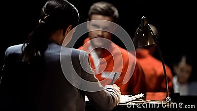 Female defense attorney writing accused prisoners statements for court, advocacy Stock Photo