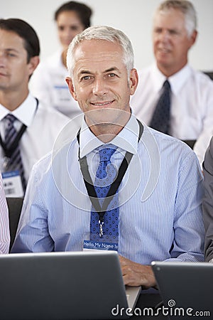 Female Delegate Listening To Presentation At Conference Making Notes On Laptop Stock Photo