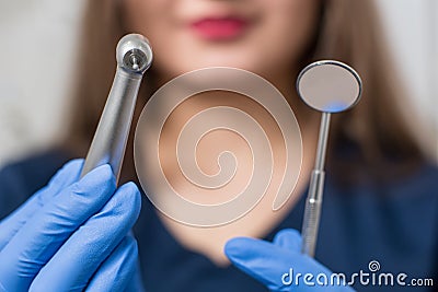 Dentist with blue gloves holding dental equipment - drill and mirror at the dental office Stock Photo