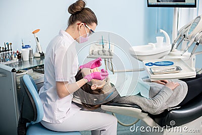 Female dentist with dental tools - mirror and probe checking up patient teeth at dental clinic office Stock Photo