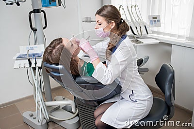 Female dentist with dental tools - mirror and probe treating patient teeth at dental clinic office Stock Photo