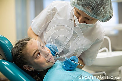 Female dentist doing teeth checkup of little girl looking with fear sitting in a dental chair Stock Photo