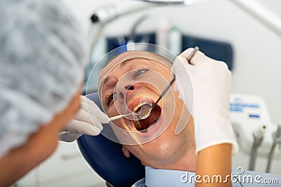 Female dentist examines the oral cavity of female patient. Dental treatment in dental clinic Stock Photo