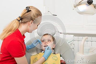 Female dentist examines the teeth of the patient child. Child mouth wide open in the dentist`s chair. Close-up Stock Photo