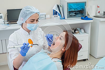 Female dentist fixed and dry dental fillings with light. Beautiful female dentist putting a filling on a tooth with caries of a Stock Photo