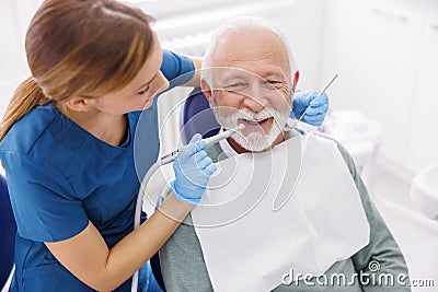 Female dentist fixing patient's tooth using dental drill Stock Photo