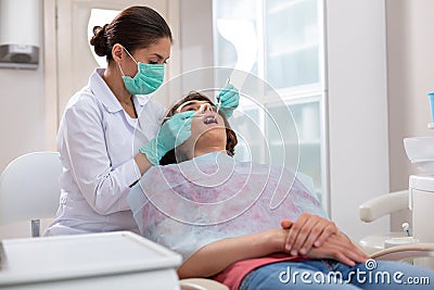 Female dentist probing her male patients teeth with dental instruments Stock Photo