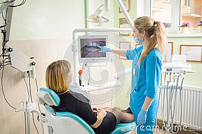 female dentist showing photograph of teeth on computer to patient Stock Photo