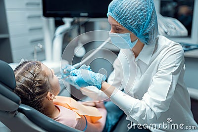 Female dentist treats teeth of little girl patient at dental office. Dentistry concept Stock Photo