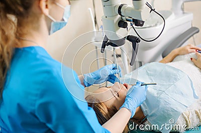 Female dentist treating caries using microscope at the dentist office Stock Photo